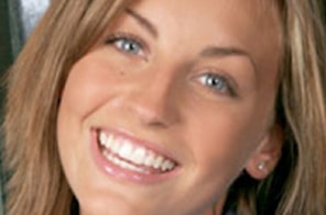 Woman smiling brightly, displaying healthy teeth and orthodontic results in professional headshot.