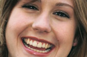 Woman smiling brightly displaying healthy, straight teeth from orthodontic treatment.