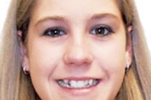 Young woman smiling at camera displaying healthy, straight teeth in professional headshot.