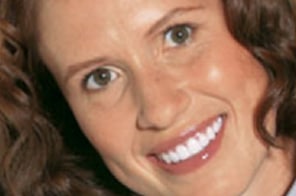Woman smiling at camera displaying results of orthodontic treatment and dental work.