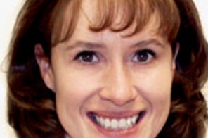 Woman smiling brightly at camera, displaying healthy teeth and orthodontic results.