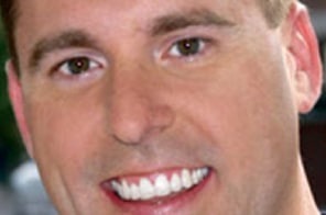 Smiling man displaying bright teeth in professional headshot for orthodontics practice.