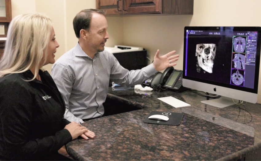 Oral surgeon in Plano Dr Bryan Elvebak reviewing 3D dental imaging with a patient for oral and maxillofacial surgery consultation.