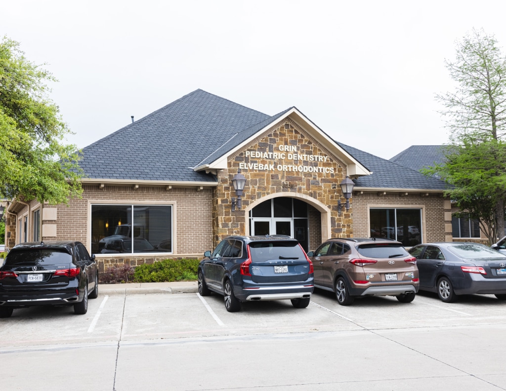 Elvebak Orthodontics brick and stone dental office building with parked vehicles and landscaping.
