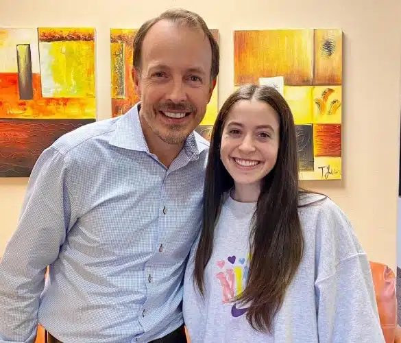 Woman in dental chair holding jaw in pain during emergency dentistry visit